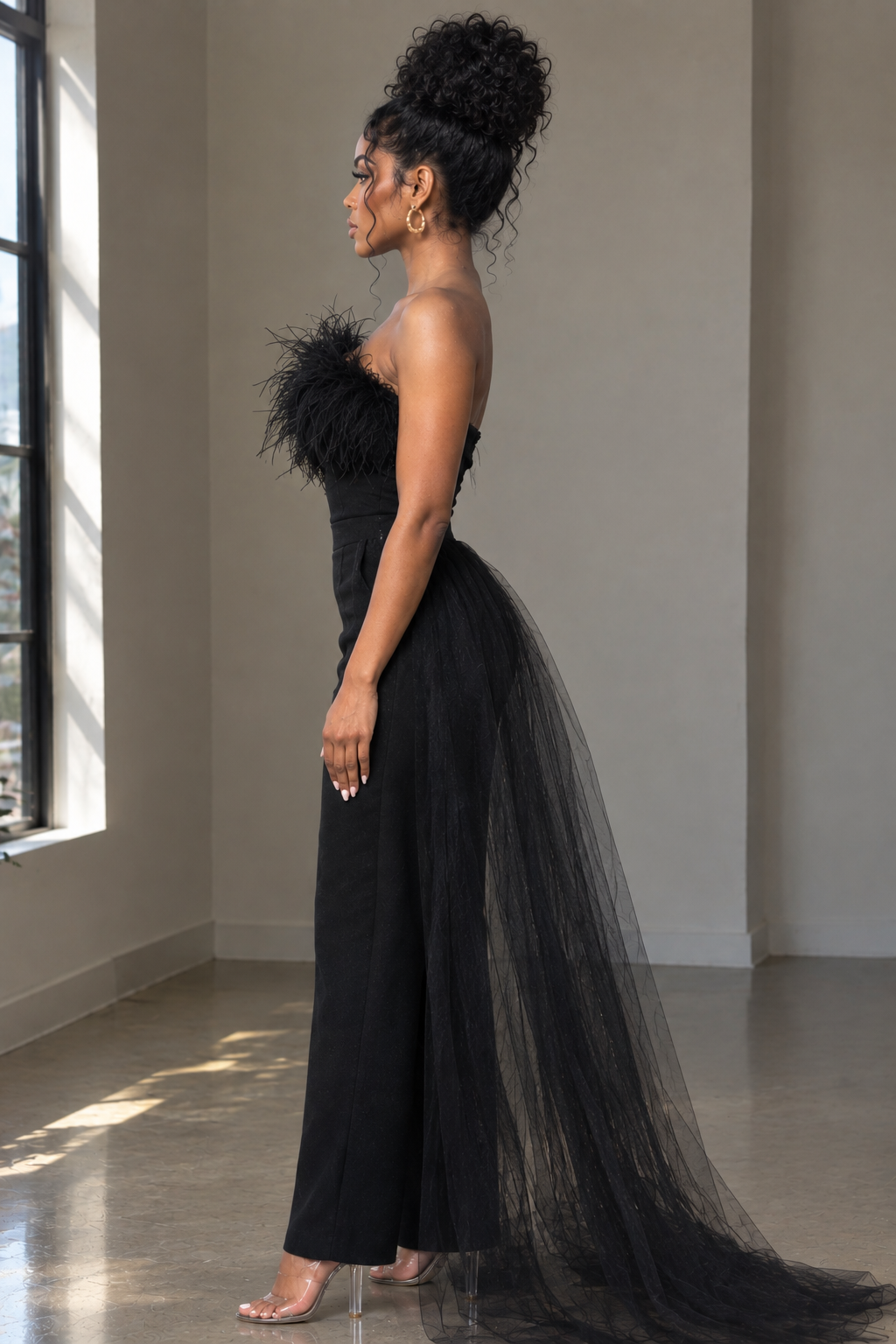 Side view of black strapless jumpsuit showing feather-style neckline trim and trailing sheer overskirt